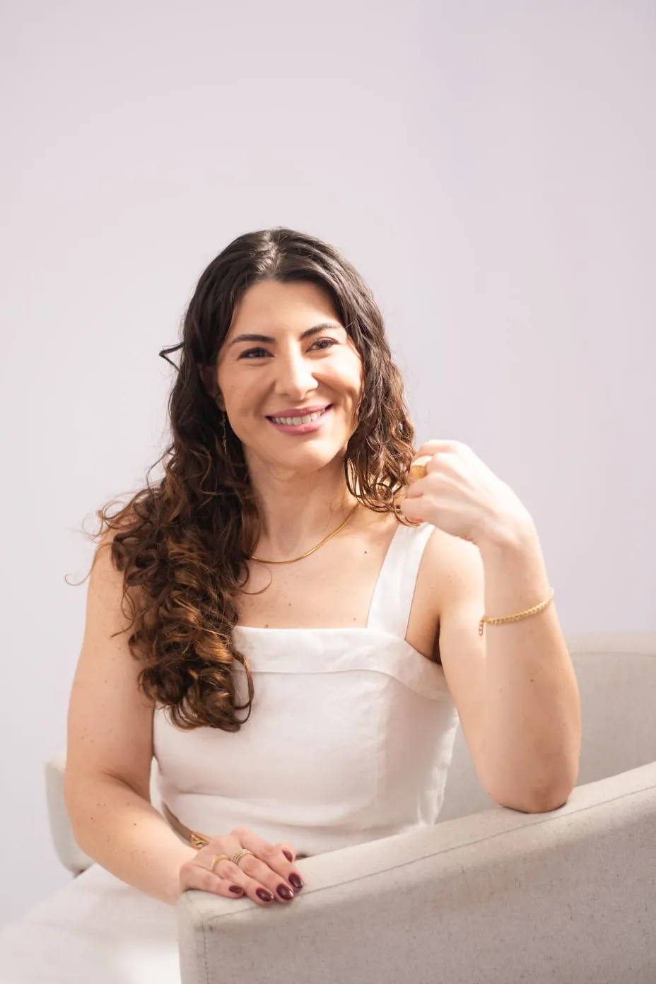 Dra. Milena Amaro sorrindo, sentada em poltrona clara
